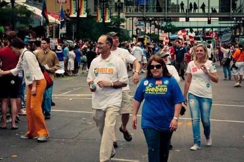 Rep. Kate Knuth greets a spectator as Rep. Tim Mahoney, Rep. Jim Davine, former Rep. Karla Bigham, and Rep. Carly Melin march at Twin Cities Pride.